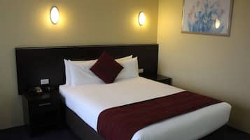 A hotel room with a large bed, two bedside tables, a nightstand, and two wall-mounted lights.