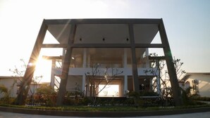A modern building with a geometric facade, large windows, and a landscaped garden area.