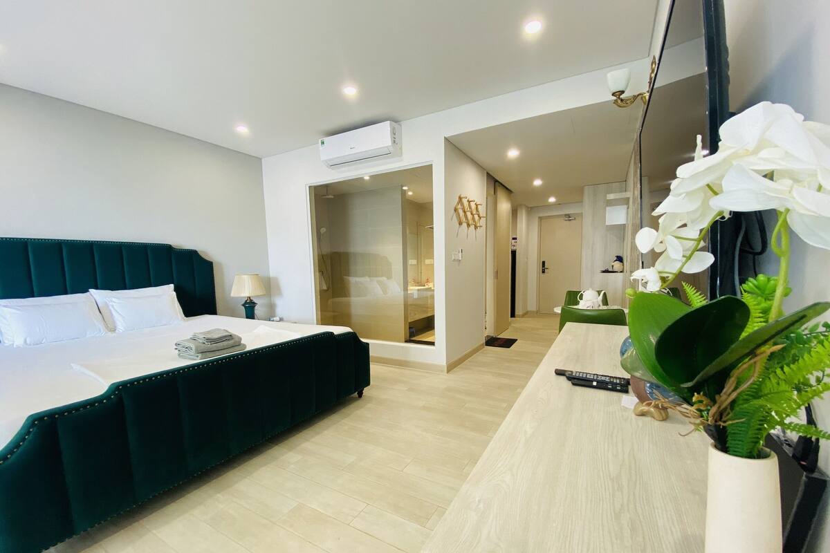 Una habitación de hotel moderna con una cama grande, una mesita de noche, un espejo y una planta en maceta.