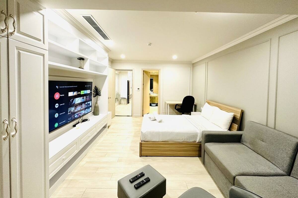 Una habitación de hotel con cama, sofá, televisor y escritorio.