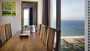 Ein Essbereich mit einem Holztisch, Stühlen und Blick aufs Meer.
