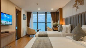Ein Hotelzimmer mit zwei Betten, einem Fernseher, einem Schreibtisch mit Stuhl und Blick aufs Meer.