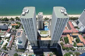 Ein Hochhaus-Hotel mit Innenhof, umgeben von weiteren Gebäuden und einem Strand im Hintergrund.