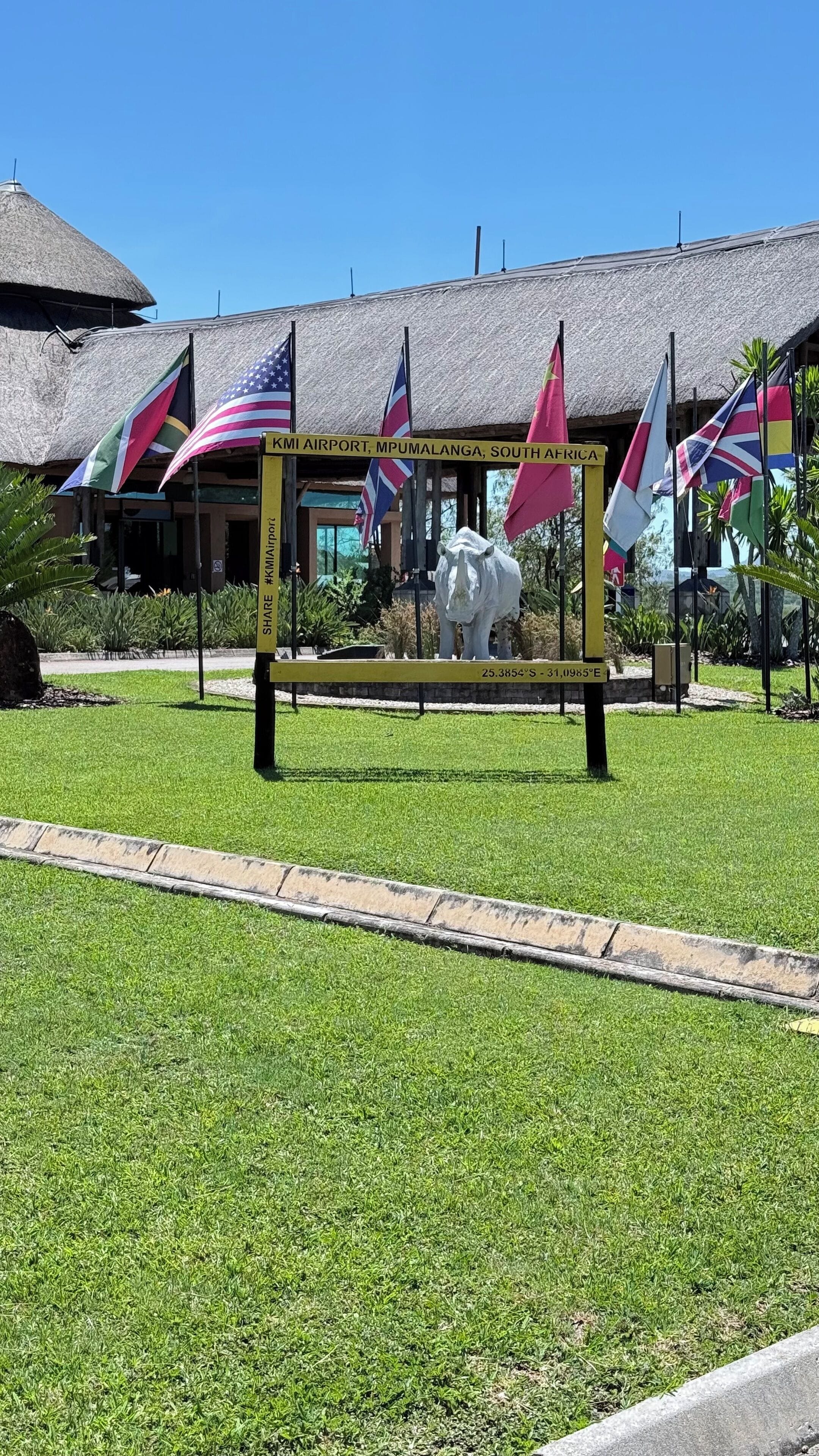 A sign with multiple national flags and a location marker for KMI Airport, Mpumalanga, South Africa.