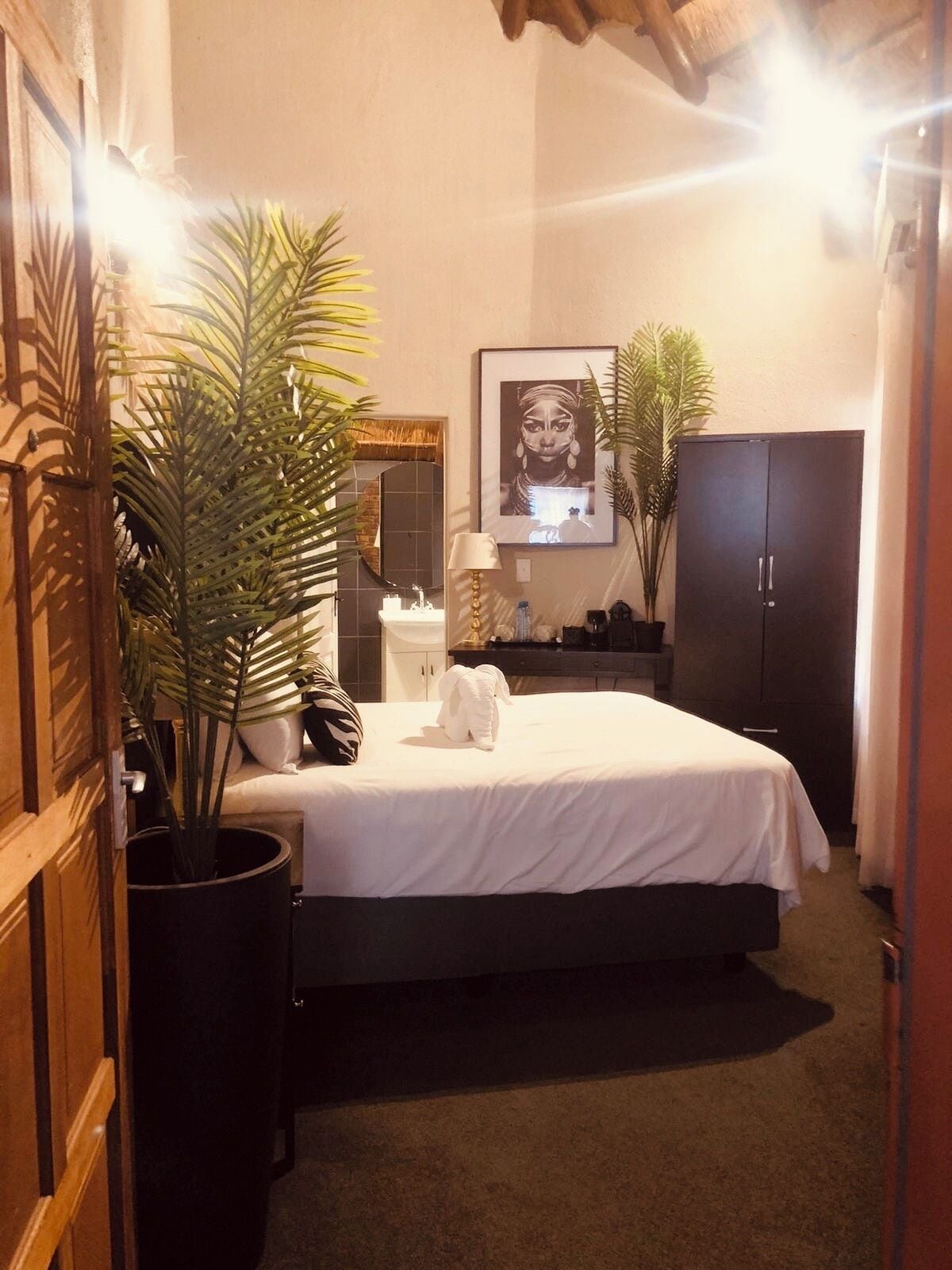 Ein Schlafzimmer mit Bett, Nachttisch, Spiegel, Kleiderschrank und einem Blumentopf.