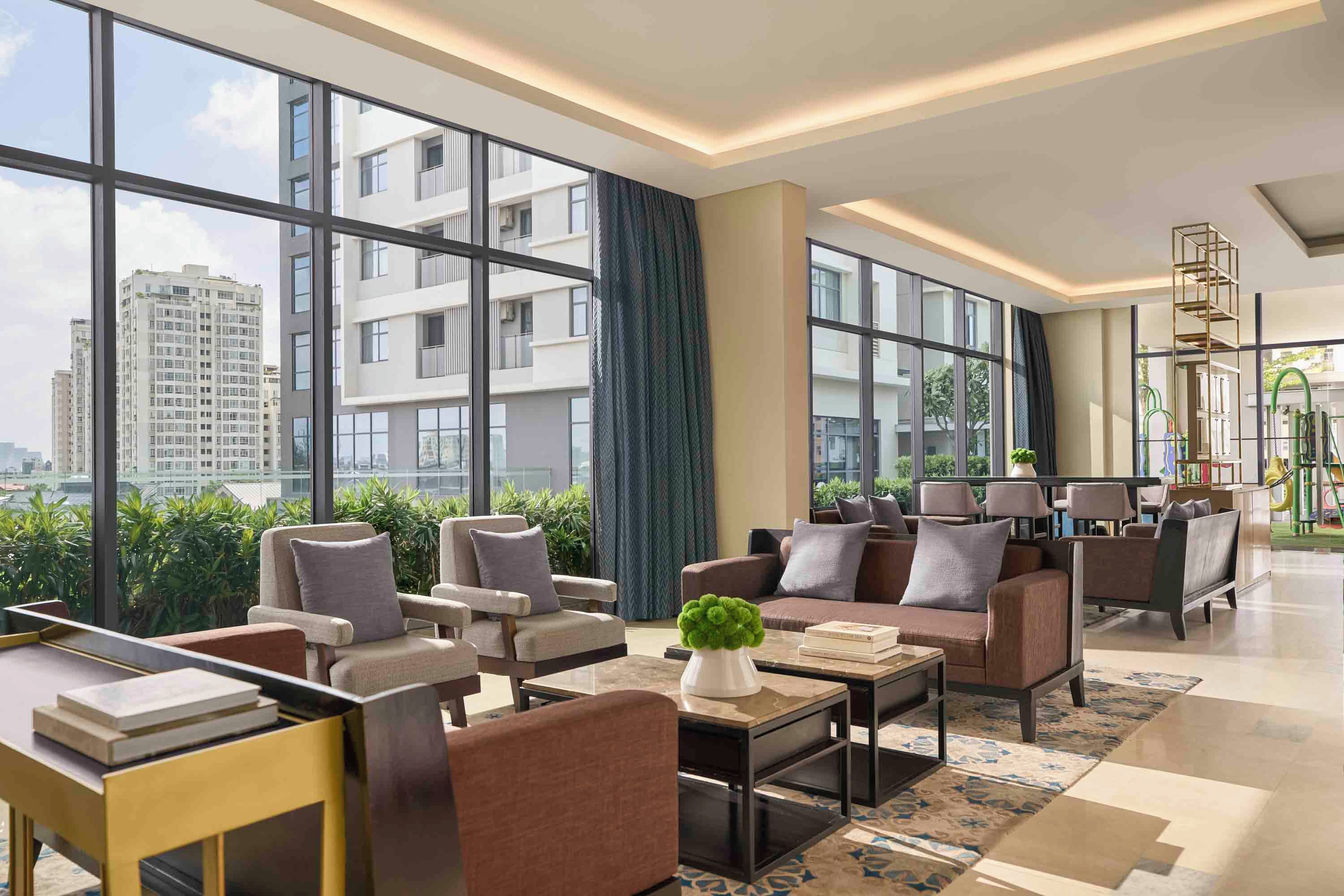 A spacious hotel lobby with large windows, comfortable seating, and a view of the cityscape.