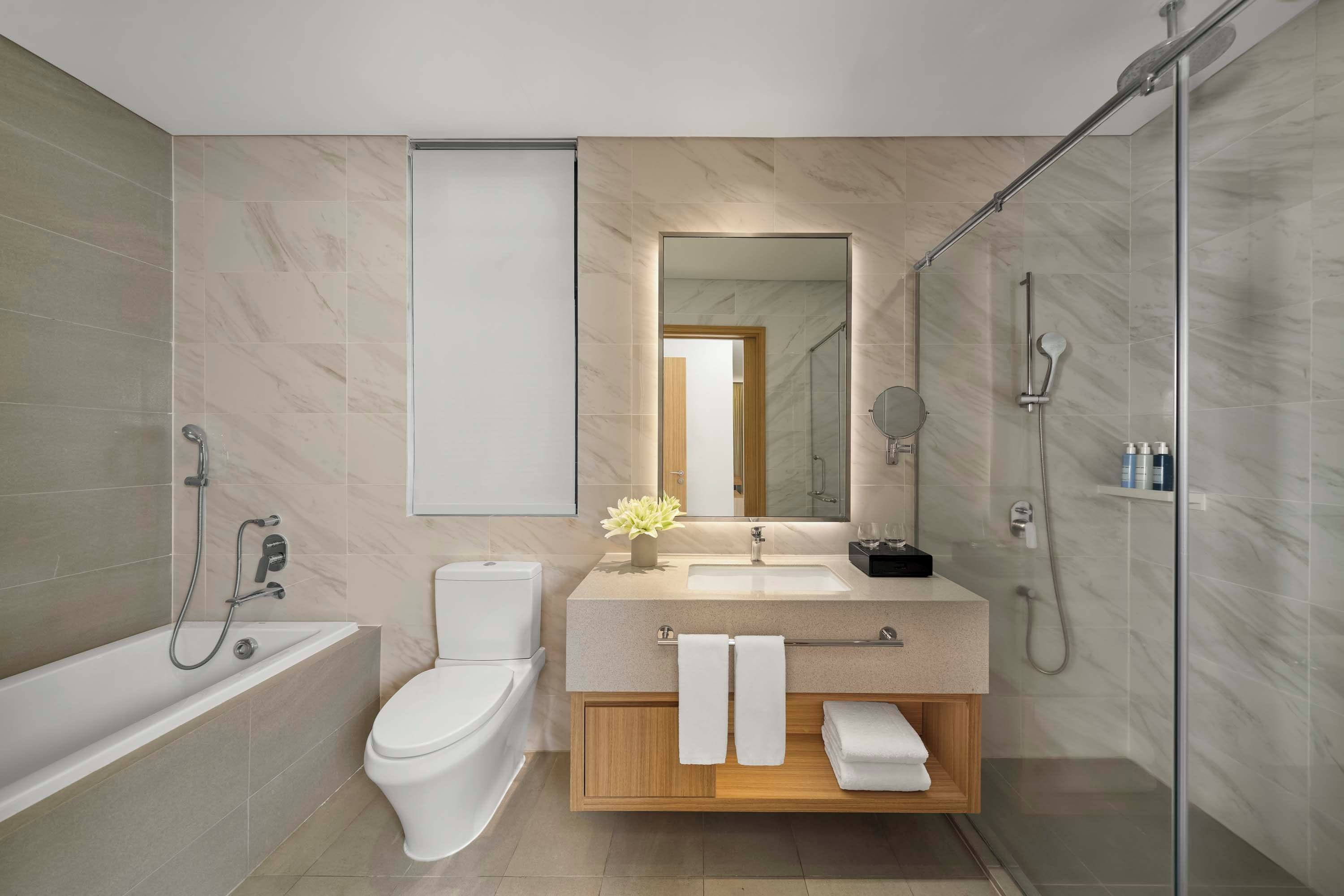 Ein modernes Badezimmer mit einer Badewanne, Toilette, Waschtisch mit Spiegel und einer Duschkabine.