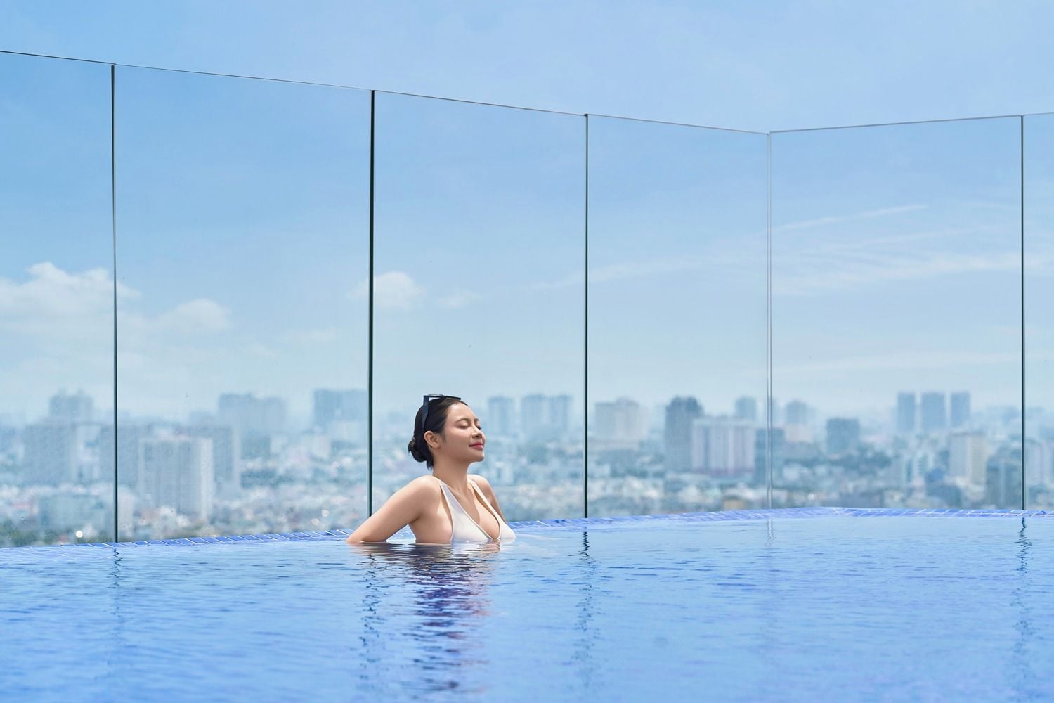 Eine Person in einem klaren, blauen Infinity-Pool mit Blick auf die Stadt.