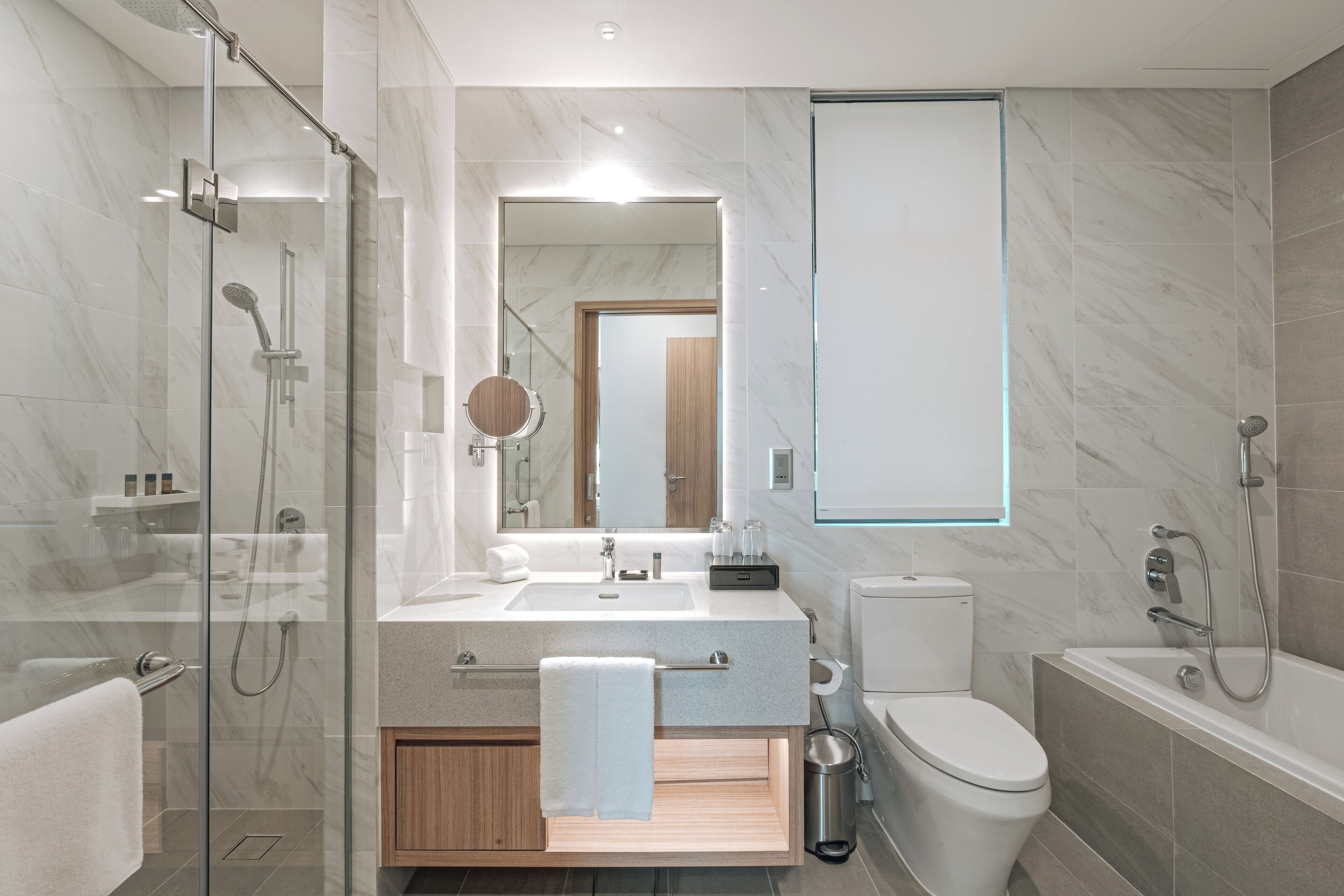 A modern bathroom with a glass-enclosed shower, a double sink vanity, a toilet, and a bathtub.