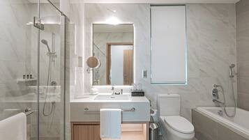 A modern bathroom with a glass-enclosed shower, a double sink vanity, a toilet, and a bathtub.