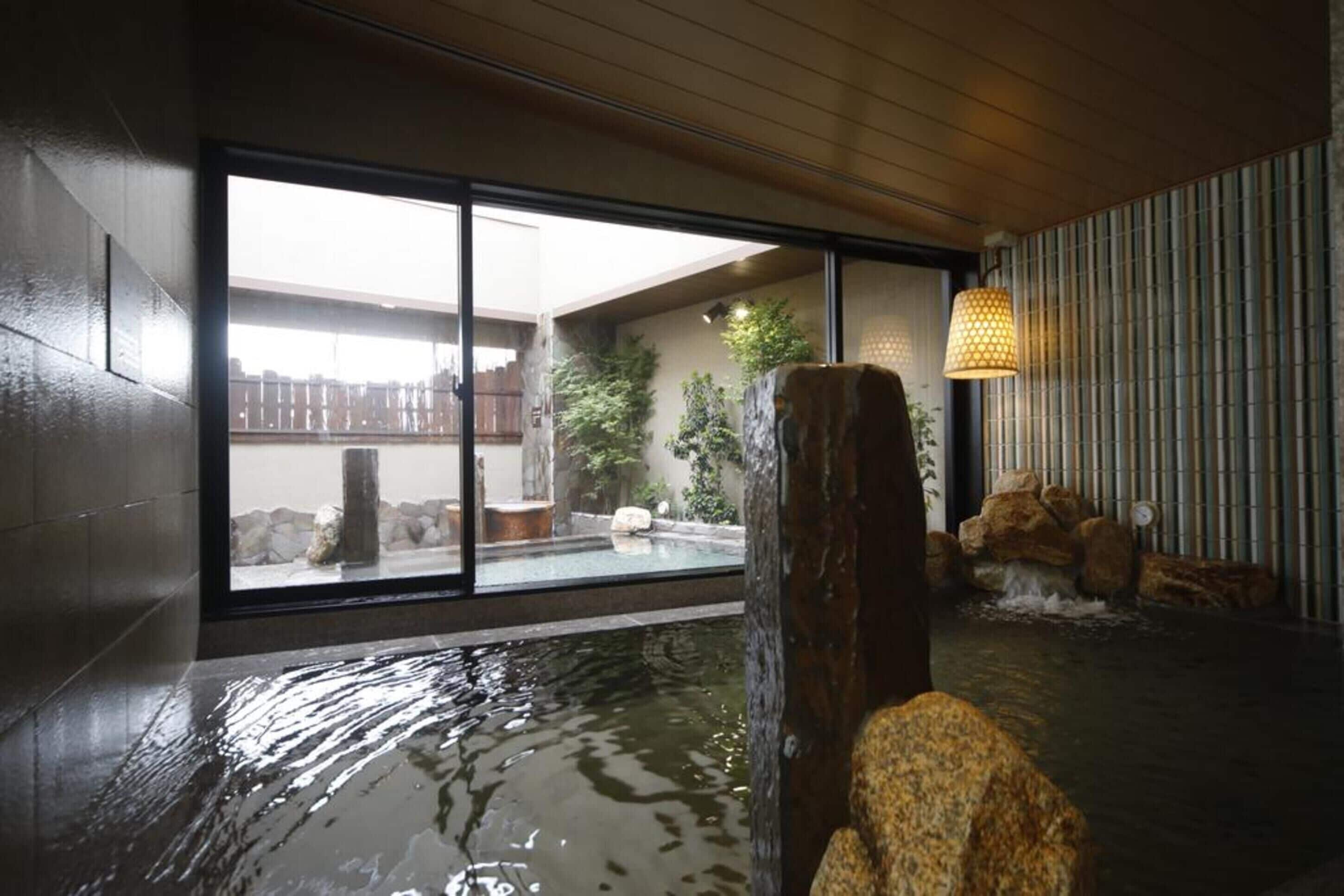 A modern indoor pool area with a view of a garden through large sliding doors.