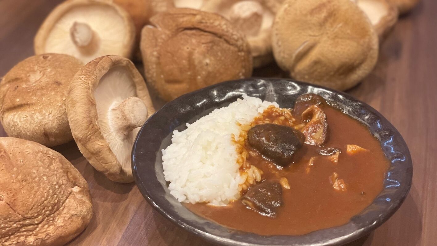A plate of white rice with a dark sauce and mushrooms, accompanied by whole mushrooms.