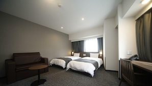 Une chambre d’hôtel avec deux lits, un canapé, une petite table et un bureau avec un téléphone.