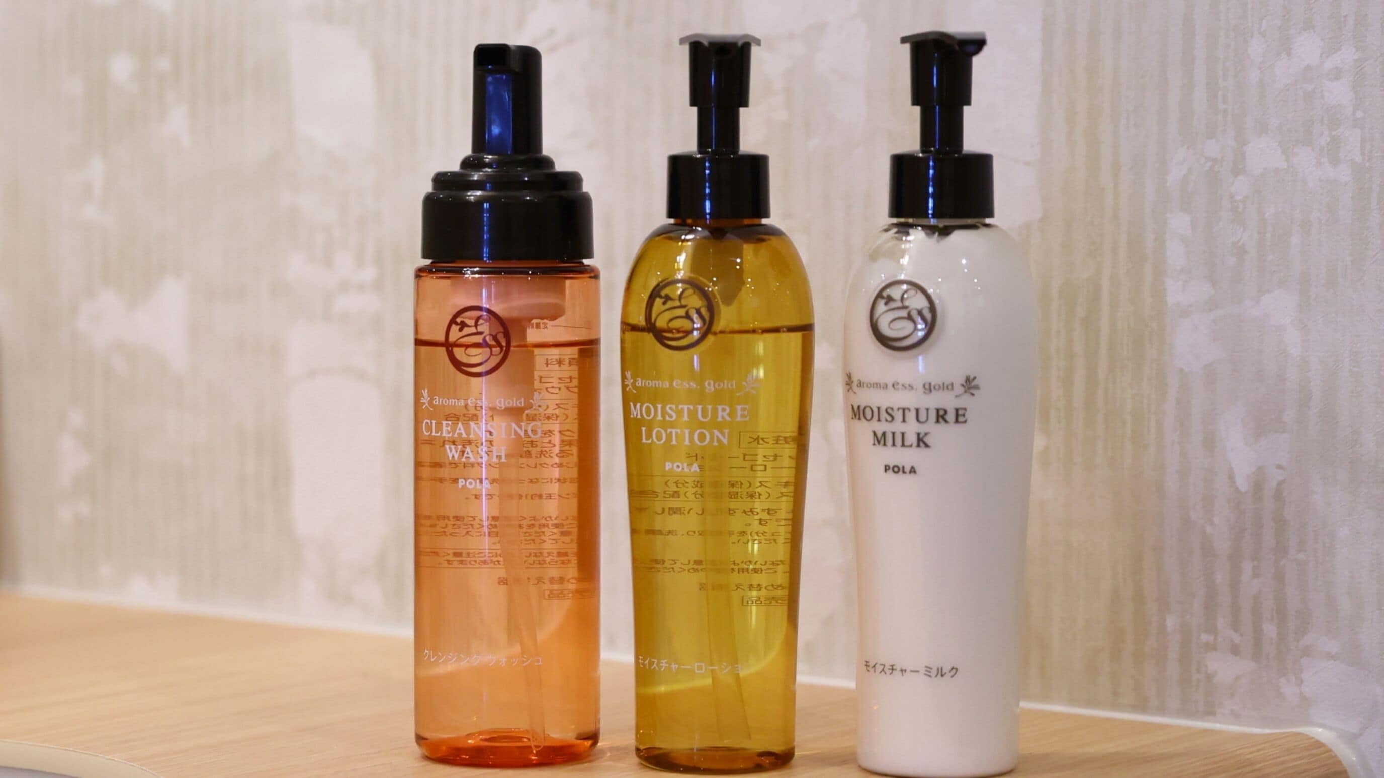 Three bottles of skincare products on a wooden surface.