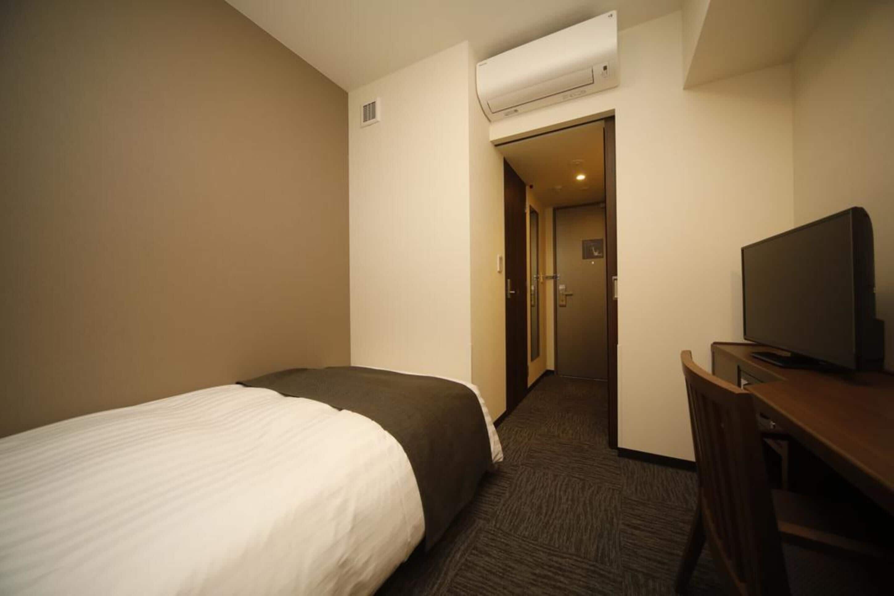 Une chambre d’hôtel équipée d’un lit, d’un bureau, d’une télévision et d’un appareil de climatisation.