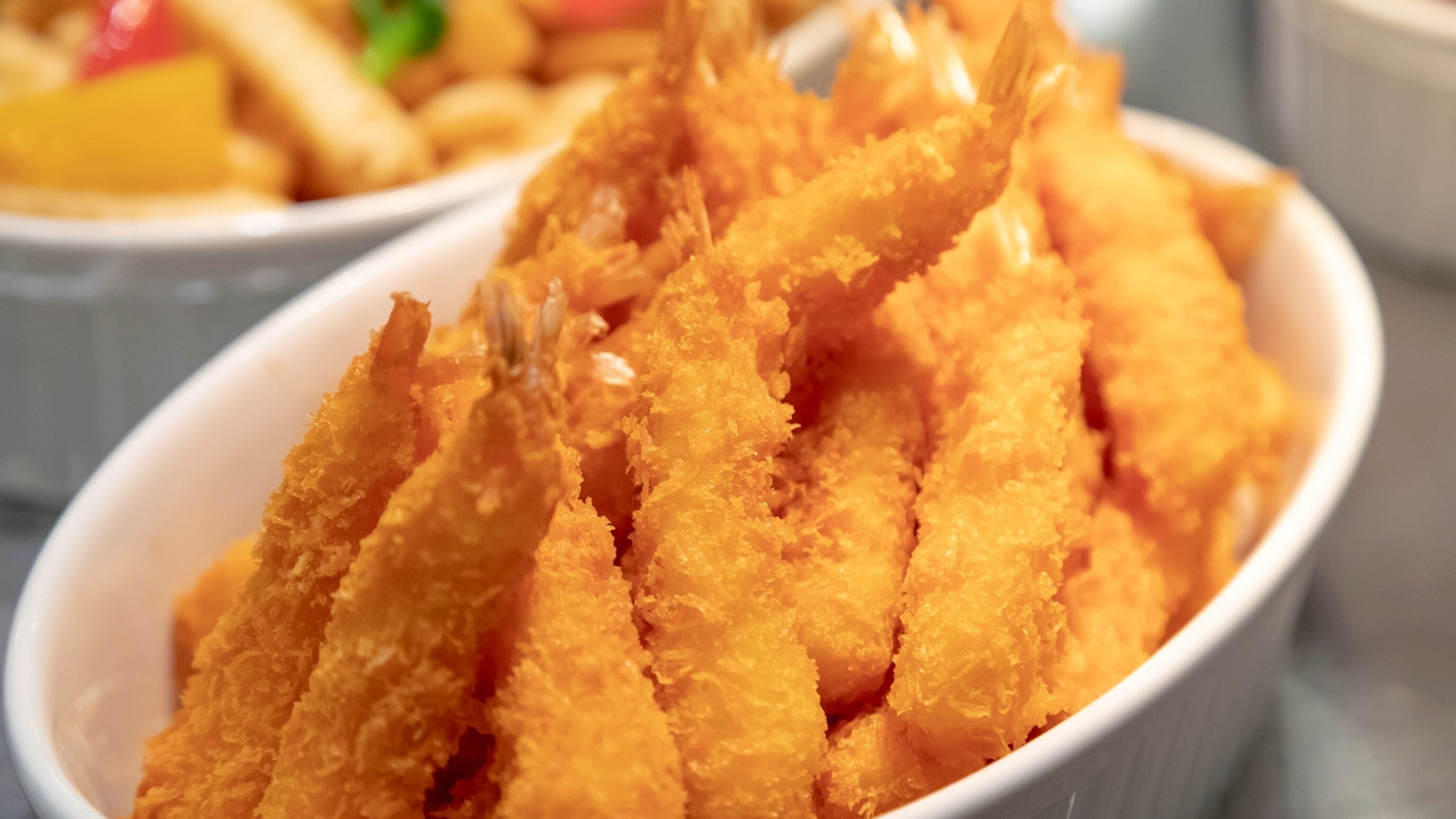 Un plat composé de morceaux de nourriture panés et frits, probablement des fruits de mer ou de la viande, servis dans un bol blanc.