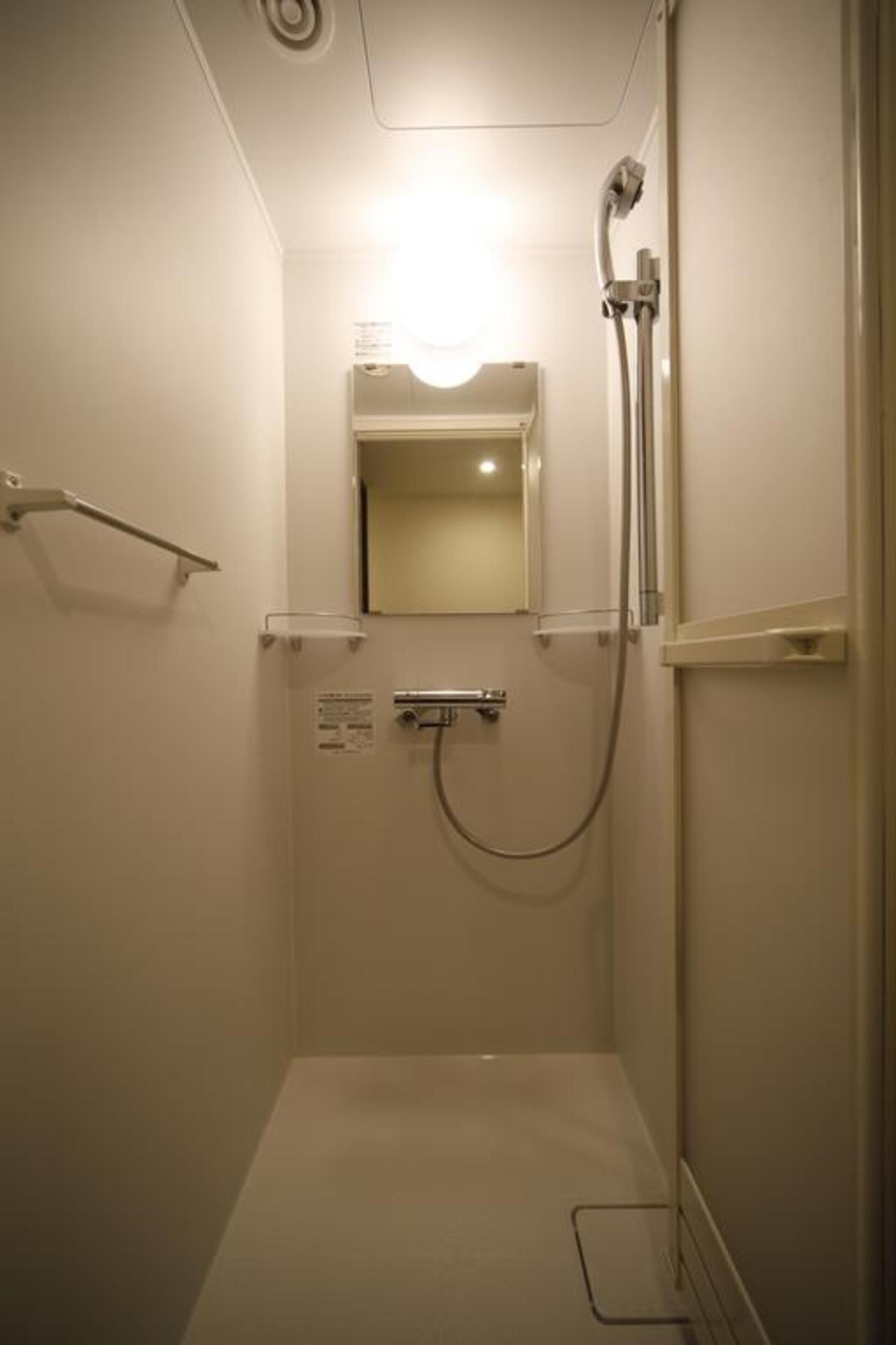 A small, enclosed shower area with a handheld showerhead and a wall-mounted faucet.