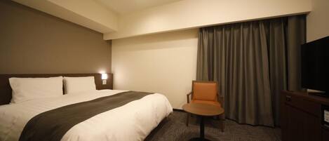 A hotel room with a large bed, a chair, a TV, and a curtain.