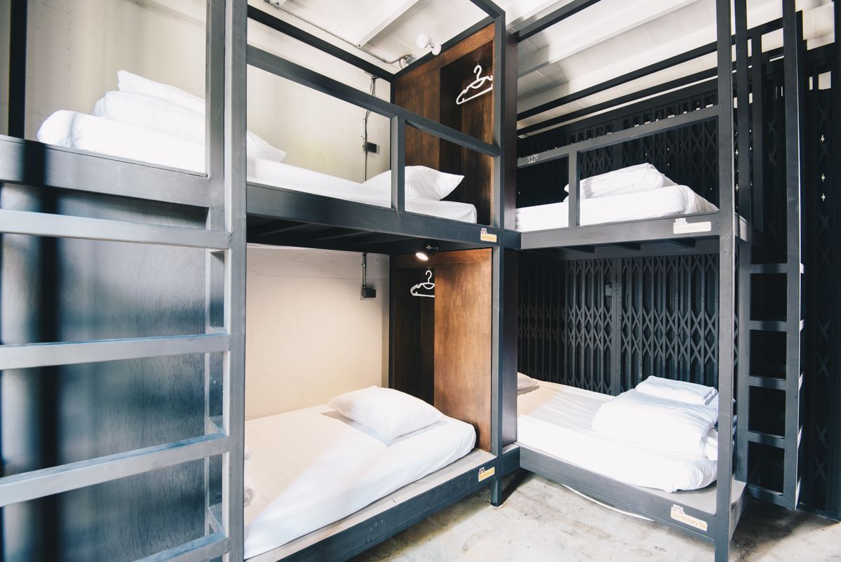 Een slaapkamer met een stapelbed, een houten garderobe en een hanglamp.