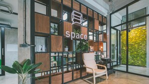 A modern interior with a 'Space' sign, wooden shelving, a potted plant, and a white chair.