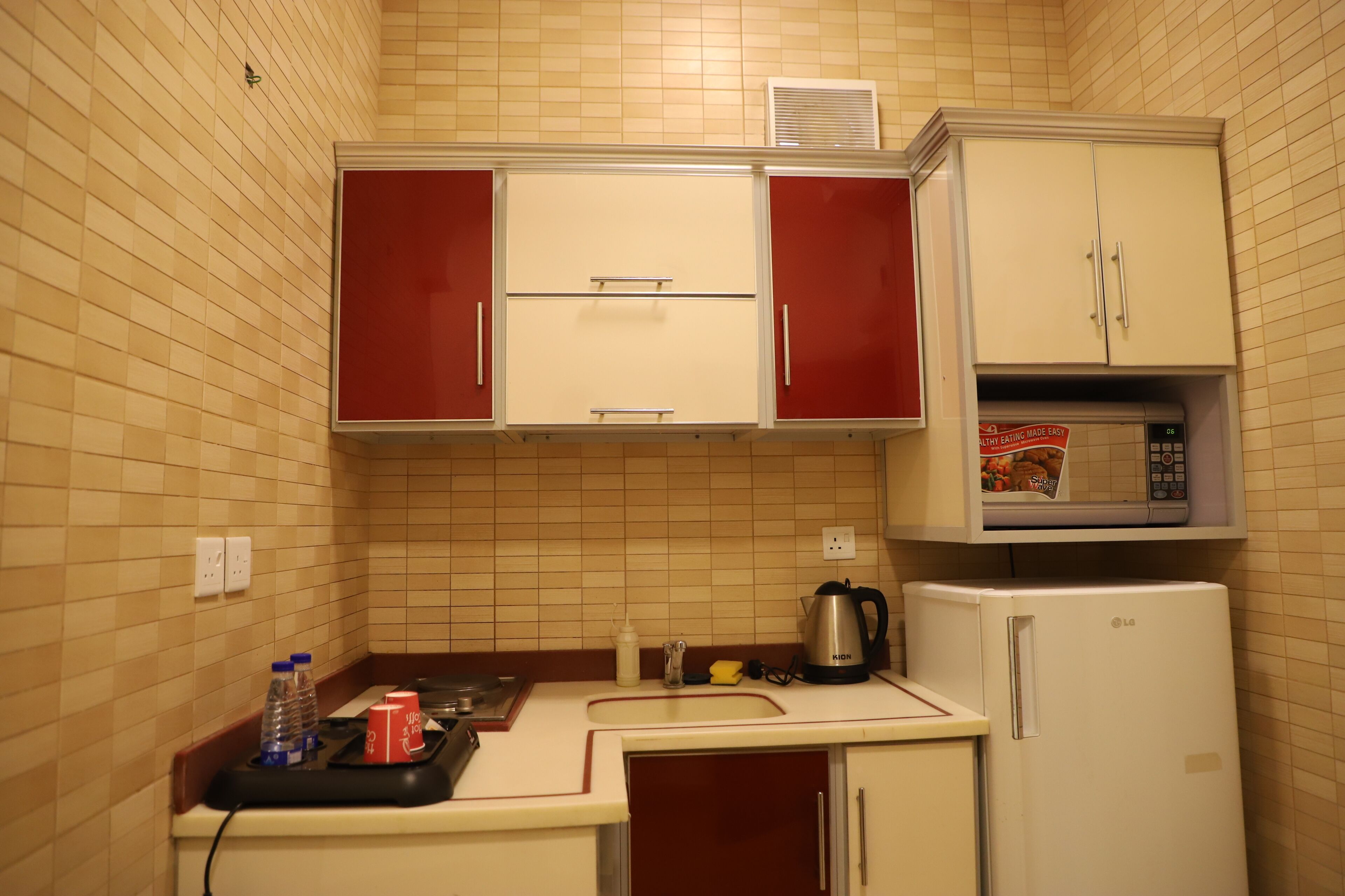 A compact kitchen with a microwave, a refrigerator, and a stove.