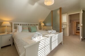 Une chambre à coucher comprenant un lit, deux tables de chevet, une commode, un miroir et une porte donnant sur une salle de bain.