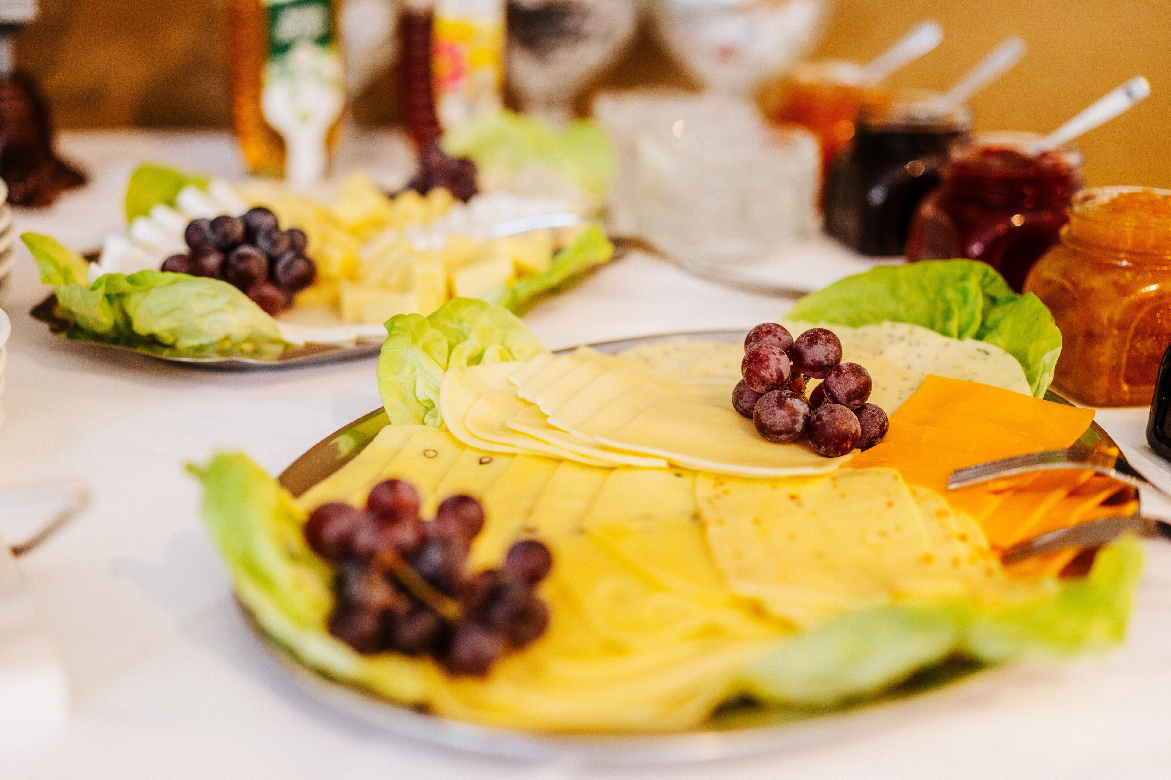 A table with a variety of food items including cheese, grapes, and leafy greens.