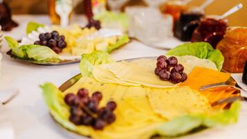 A table with a variety of food items including cheese, grapes, and leafy greens.