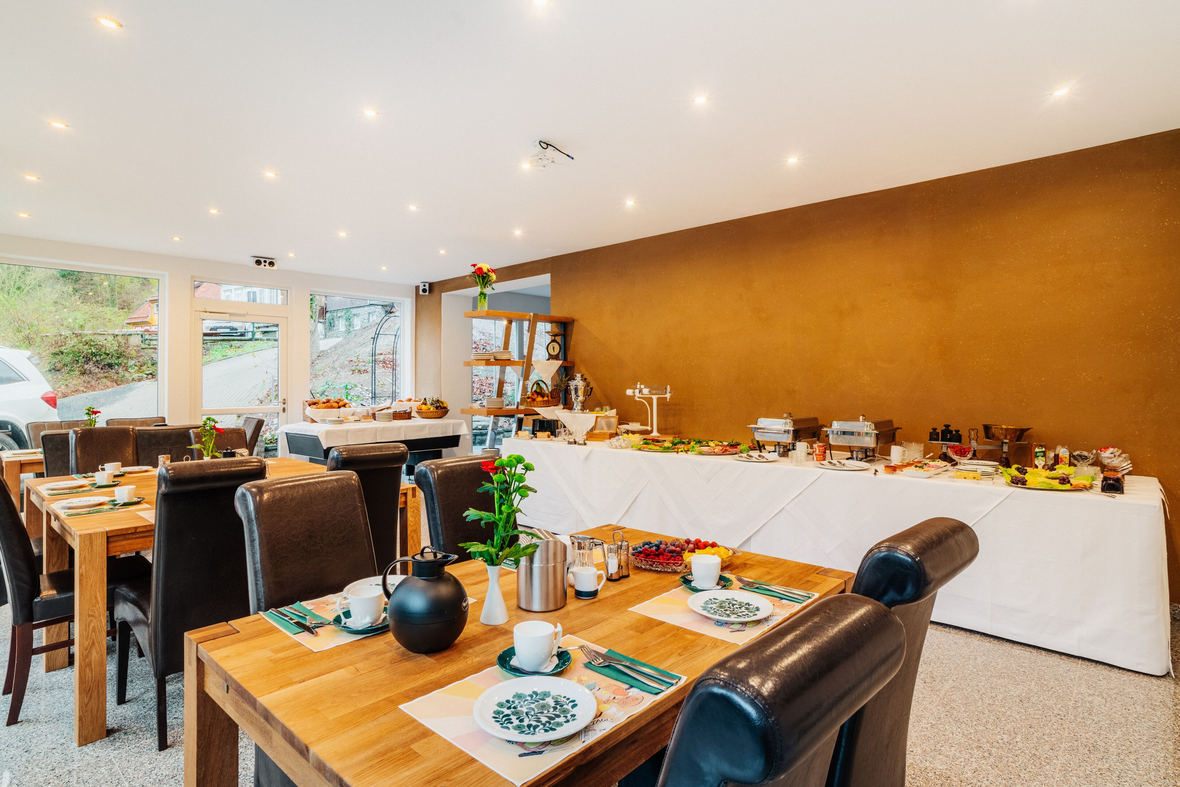 A dining area with tables set for breakfast, including plates, cups, and cutlery.