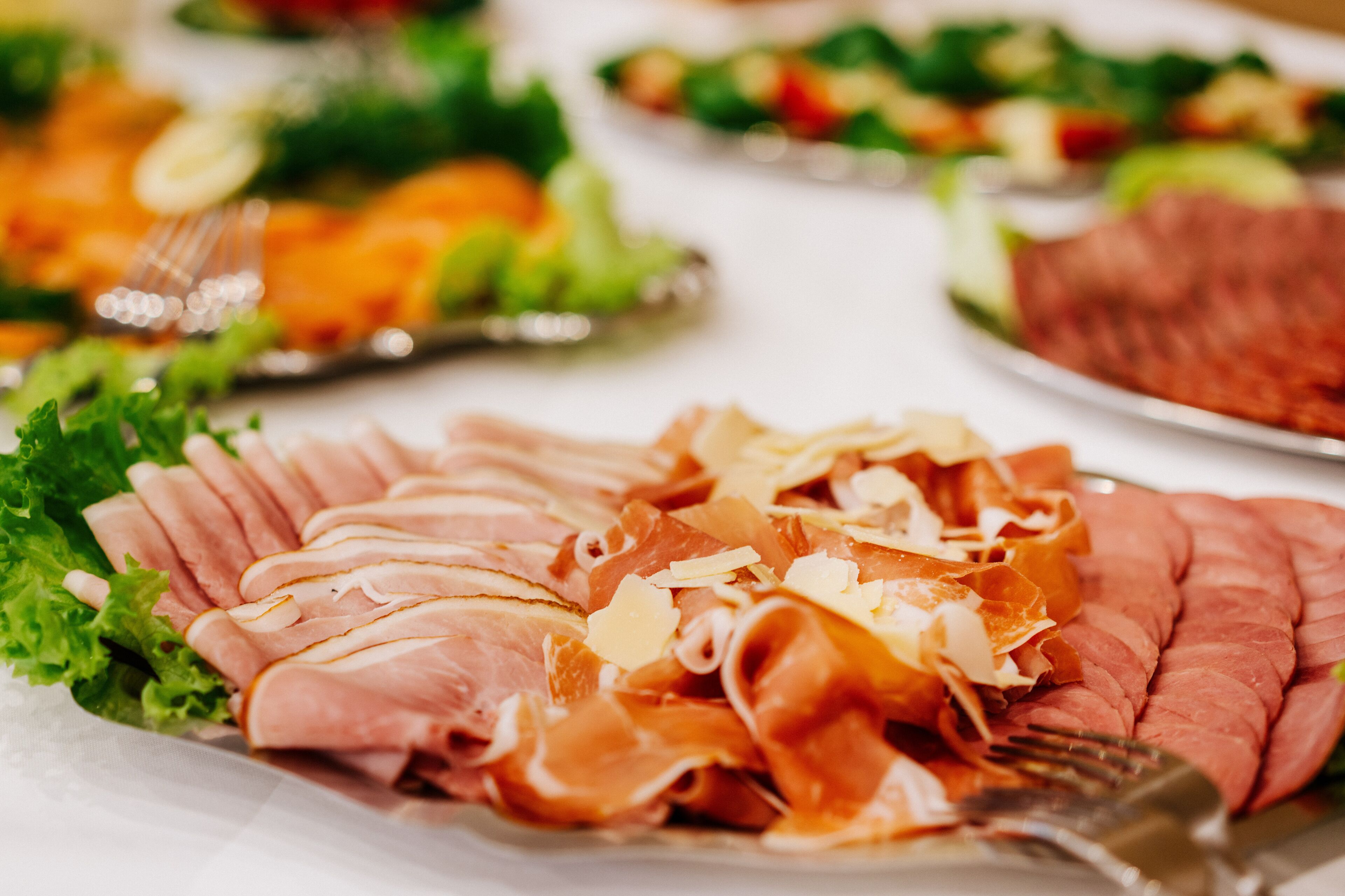 Une table garnie de divers aliments, notamment des viandes et des légumes coupés en tranches.