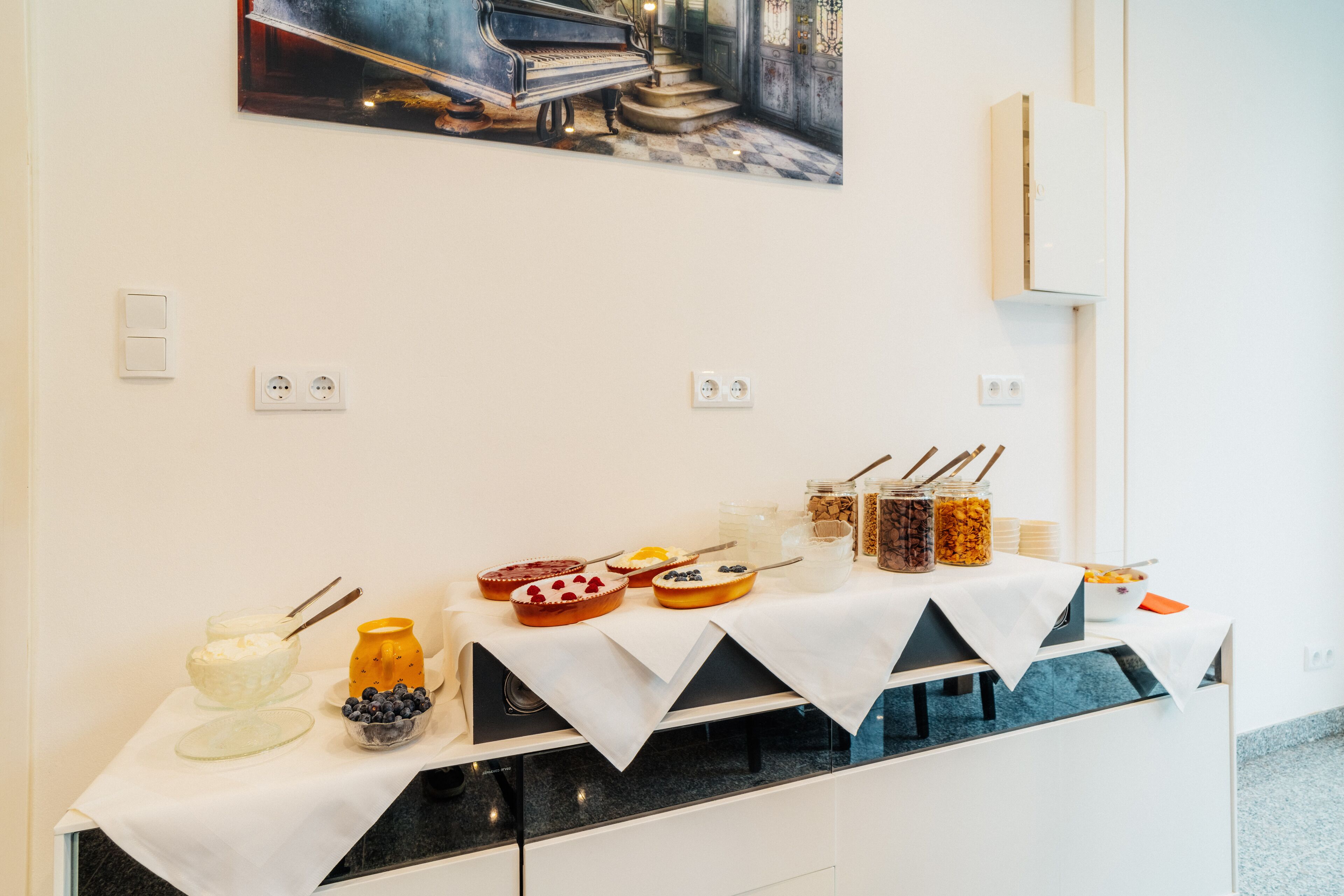 Une table de buffet garnie de divers plats et un tableau accroché au-dessus.