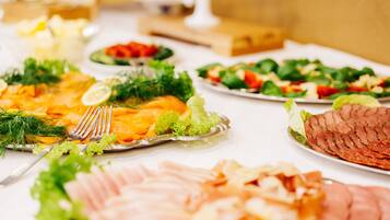 A buffet table with various dishes including sliced meats, salads, and garnishes.