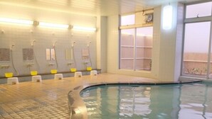 An indoor swimming pool with a tiled floor, multiple shower cubicles, and a large window providing a view of the outside. - Sunset Susami (Susami)