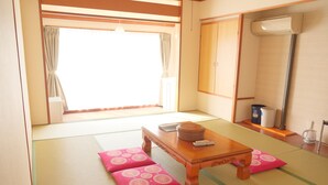 A traditional Japanese room with tatami flooring, a wooden table with cushions, a window with curtains, and a radiator. - Sunset Susami (Susami)