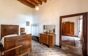 Ein Schlafzimmer mit einem hölzernen Bett, einem Schminktisch, einem Spiegel und einem Kleiderschrank.