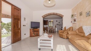 A spacious living room with a large sofa, a television, and a white coffee table. - 2 bedroom cozy home in Scarlino -GR- (Scarlino -GR-)