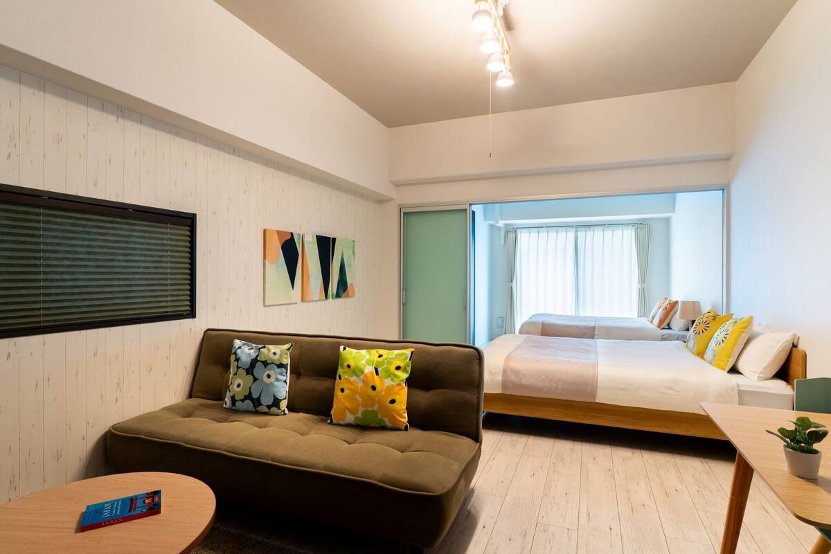A modern hotel room with a sofa, a bed, a small table, and a window.