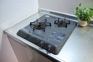 A kitchen with a gas stove and a potted plant. - nedoco OSAKA SHINSAIBASHI (formerly: FORESTAY Shinsaibashi) (Osaka)