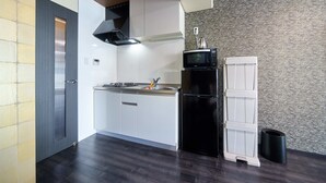 Una cocina moderna con armarios blancos, un refrigerador negro y un microondas.
