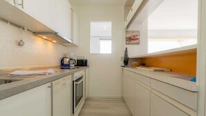 Una cocina estrecha con armarios blancos, una cafetera y un tostador.