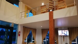 Un hall d’hôtel avec un plancher en bois, un comptoir d’accueil, un téléviseur et un escalier menant à l’étage supérieur.