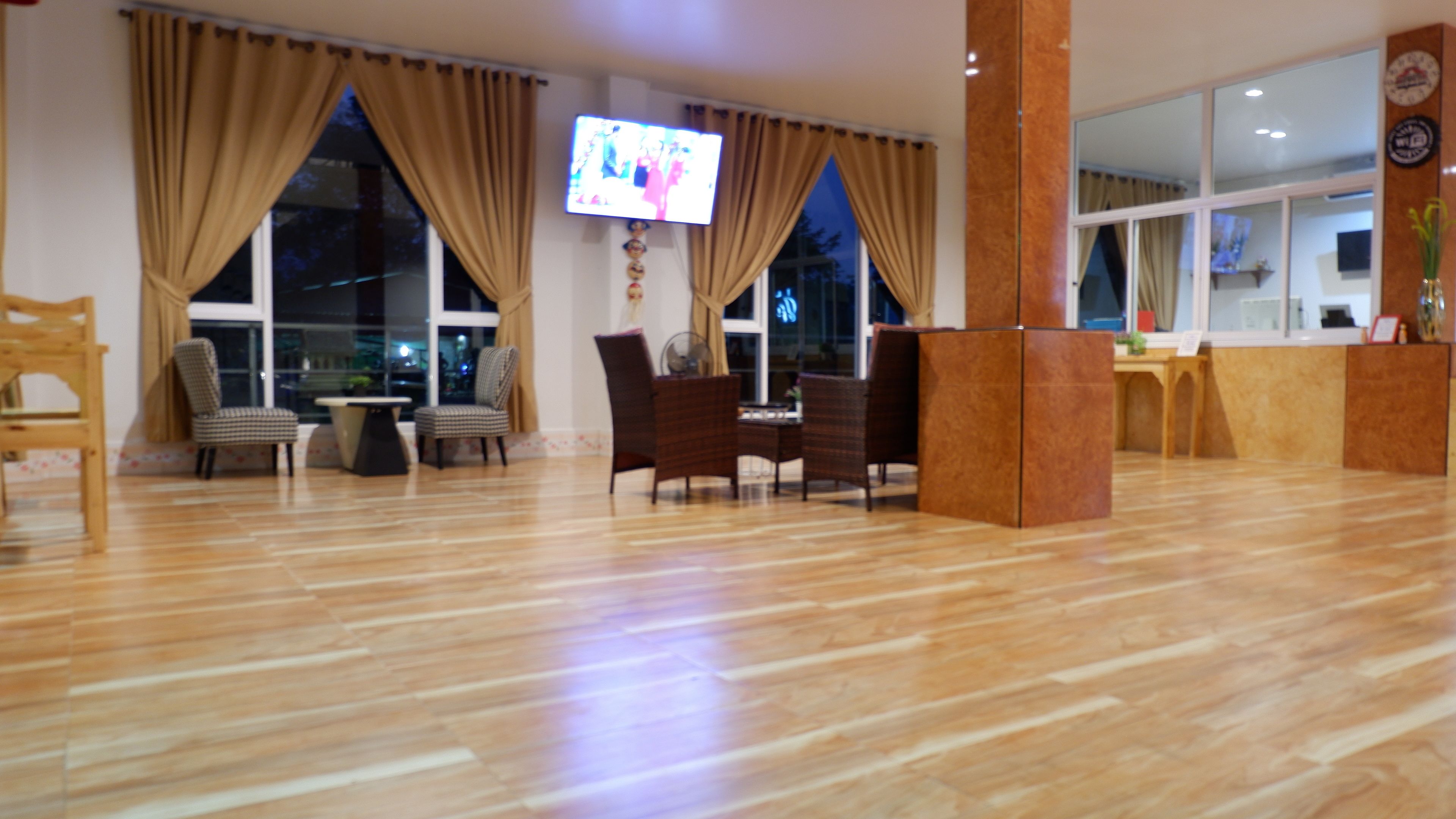 A spacious room with wooden flooring, a television mounted on the wall, and a reception desk.
