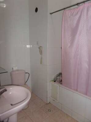 Un baño con lavamanos, inodoro y cortina de ducha.