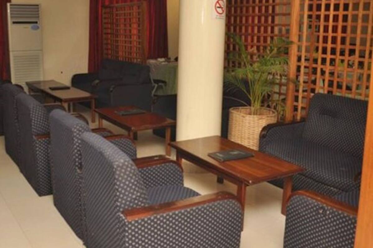 A seating area with sofas and tables, a plant, and a wooden partition.