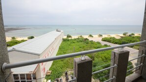 Uitzicht vanaf een balkon op een strand, met een gebouw op de voorgrond.