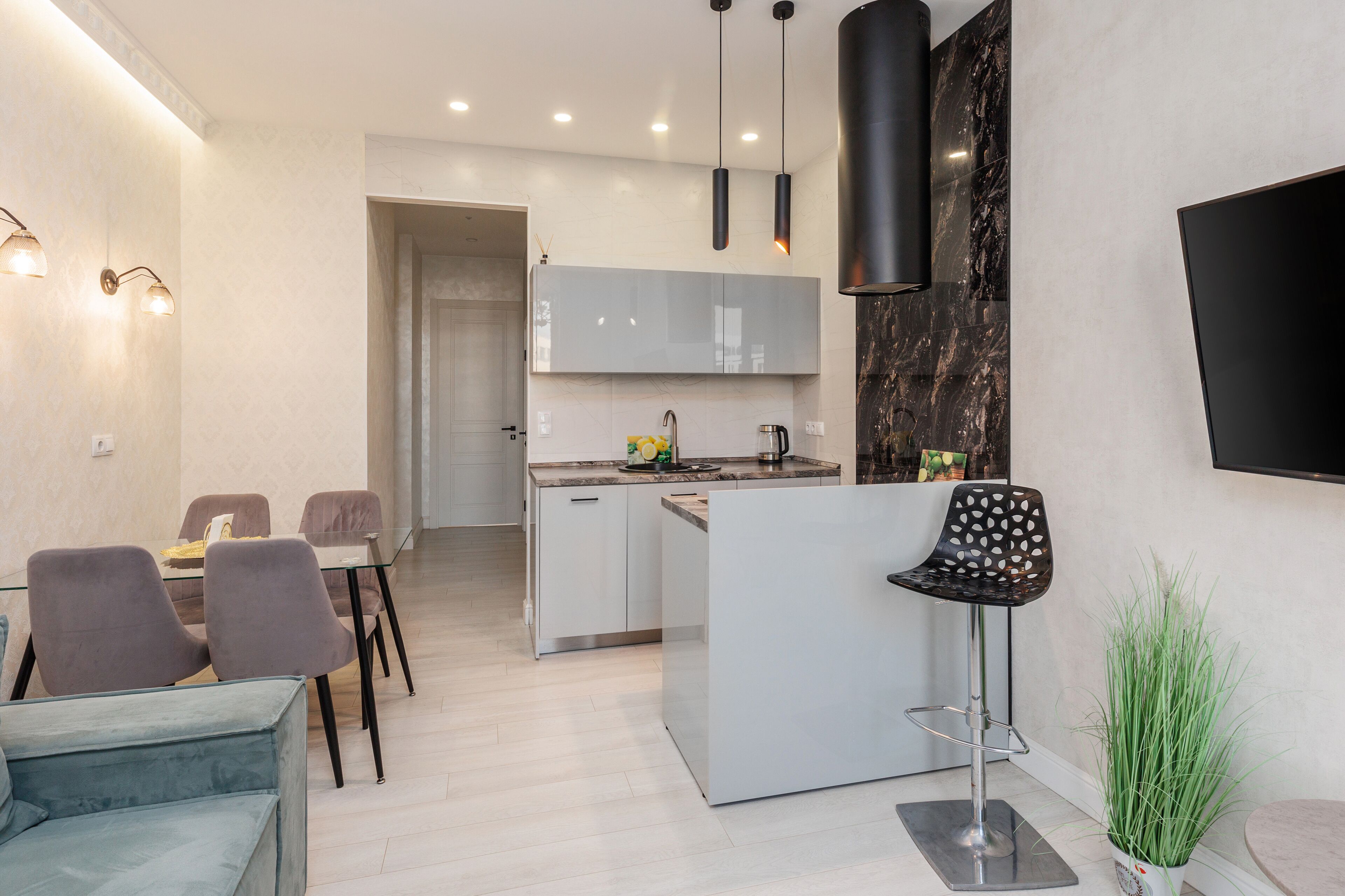 A modern kitchen with a central island, a dining area with a sofa and chairs, and a small bar area with a stool.