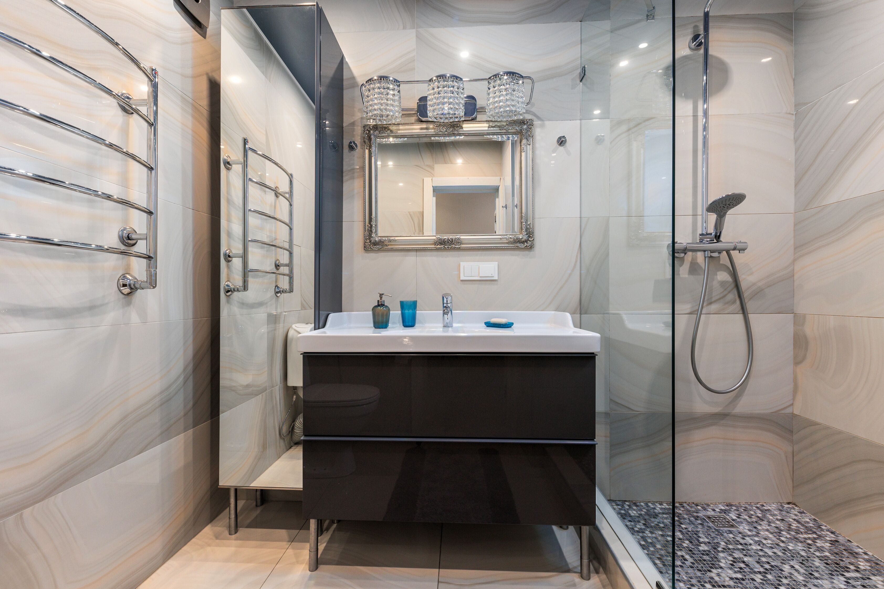 A modern bathroom with a glass shower enclosure, a vanity with a mirror, and a towel rack.