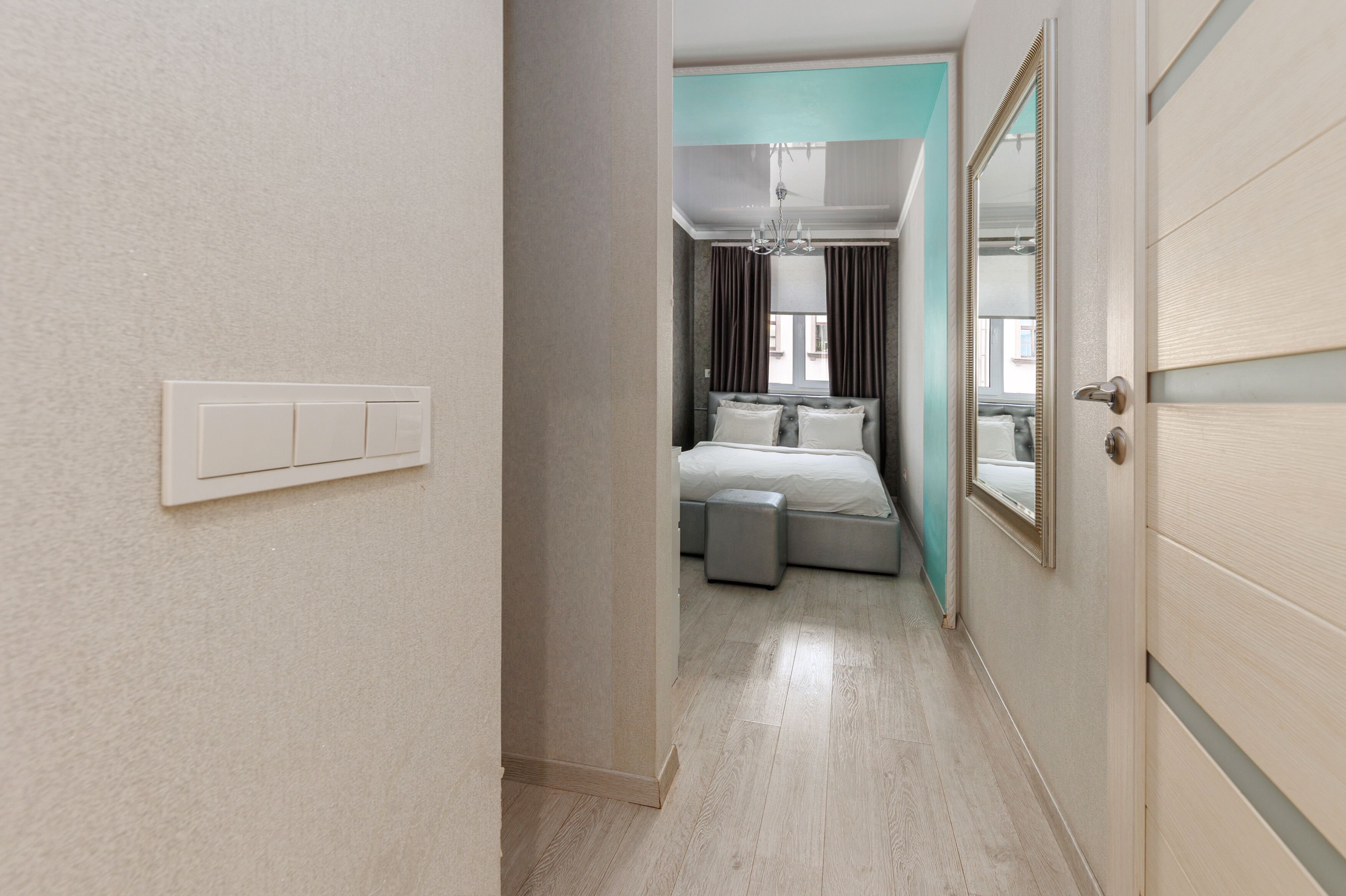 Een hotelkamer met een bed, een zithoekje, een spiegel en een deur.