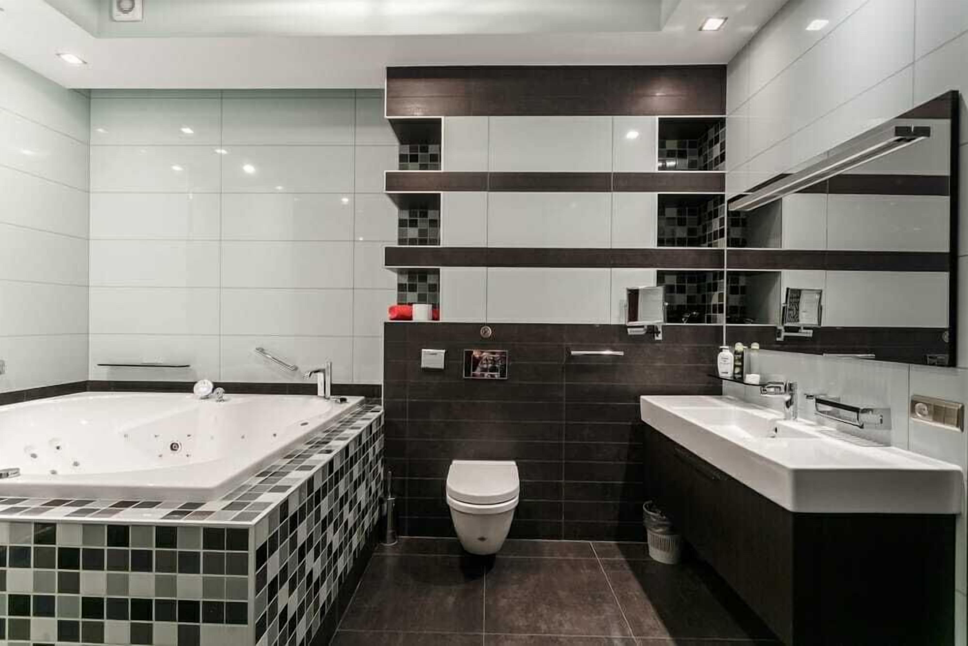 Un baño moderno con una bañera grande, un inodoro y un tocador con espejo.