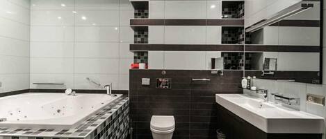 Un baño moderno con una bañera grande, un inodoro y un tocador con espejo.